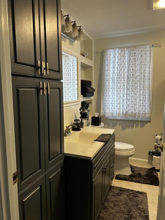 bathroom with tile patterned flooring, vanity, toilet, and baseboards