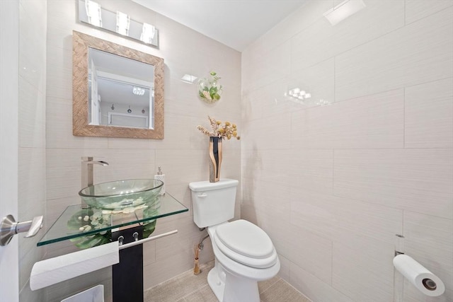 bathroom featuring tile patterned floors, sink, tile walls, and toilet