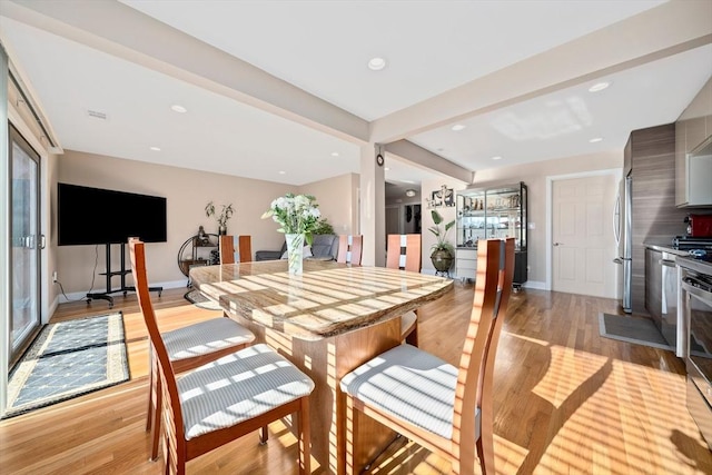 dining area featuring beamed ceiling and light hardwood / wood-style flooring