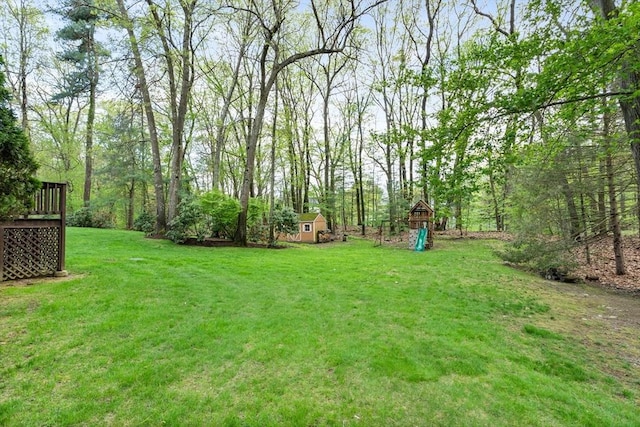 6 Shannon Cir, Westford, MA 01886 - view of green lawn featuring a storage unit, an outbuilding, a deck, and a playground