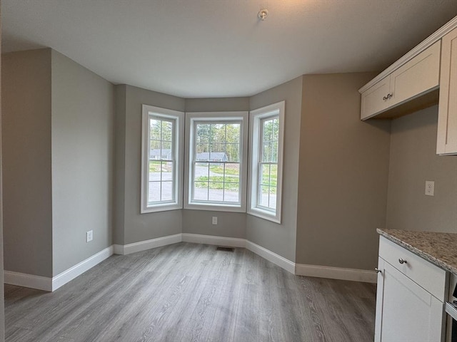 unfurnished dining area with baseboards, visible vents, and light wood finished floors