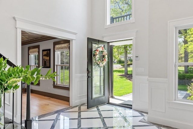 31 Alford Cir, Concord, MA 01742 - entrance foyer featuring inlaid floor details, plenty of natural light, and a wainscoted wall