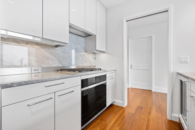 1 Dalton St Unit 3302, Boston, MA 02199 - kitchen with black oven, white cabinetry, light wood-style floors, backsplash, and stainless steel gas cooktop
