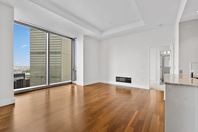 1 Dalton St Unit 3302, Boston, MA 02199 - unfurnished living room with wood finished floors, a glass covered fireplace, a tray ceiling, baseboards, and floor to ceiling windows