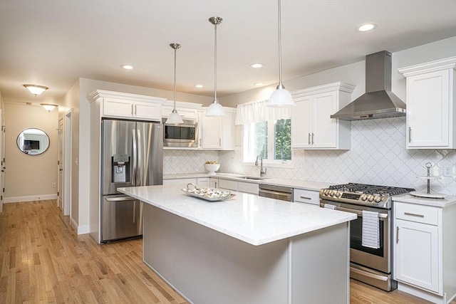 kitchen with wall chimney exhaust hood, white cabinets, and appliances with stainless steel finishes