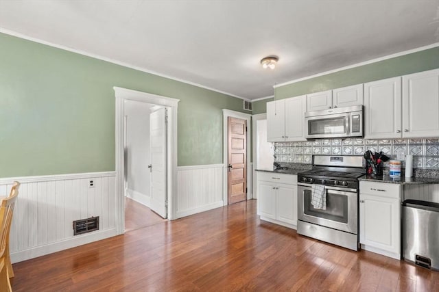 14 Forest Ave, Salem, MA 01970 - kitchen featuring stainless steel appliances, a wainscoted wall, dark wood-style floors, white cabinets, and ornamental molding
