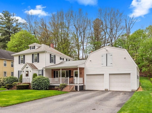 view of front of house with a front yard, a porch, a gambrel roof, and driveway