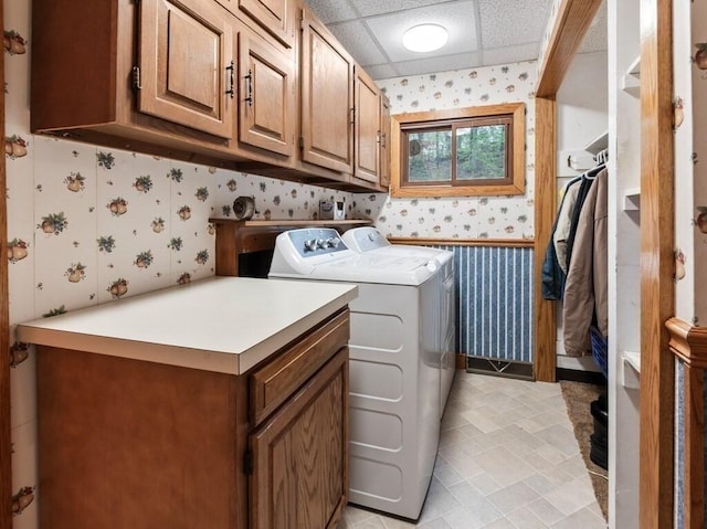 clothes washing area featuring separate washer and dryer, wallpapered walls, and cabinet space