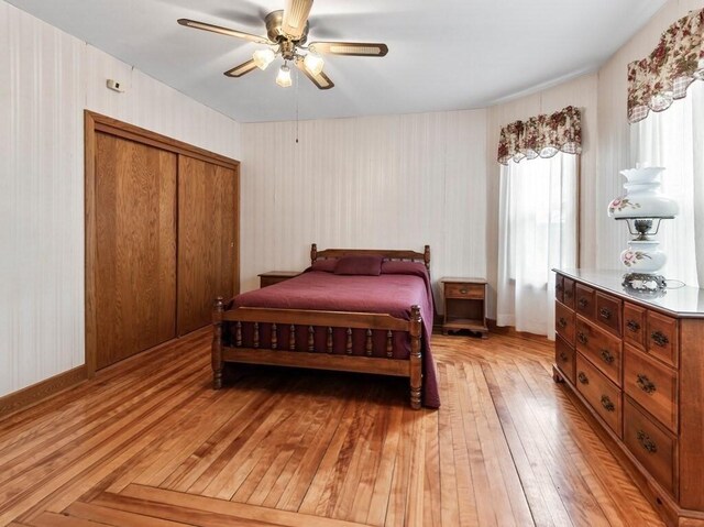 bedroom with light wood finished floors, a closet, a ceiling fan, and wallpapered walls