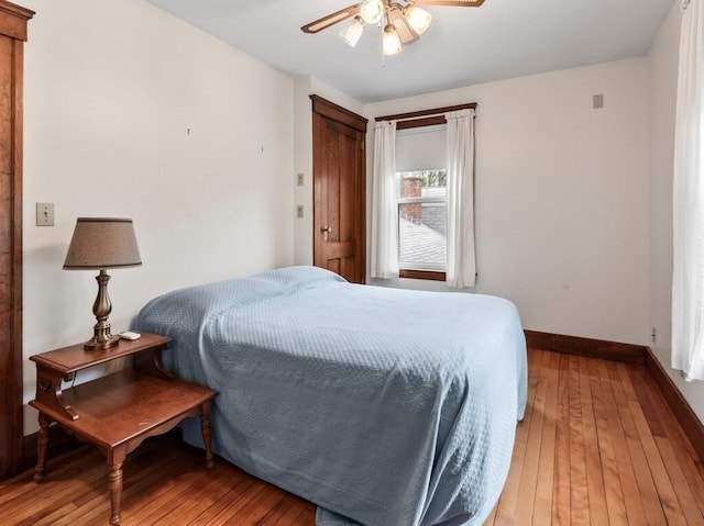 bedroom featuring baseboards, light wood-type flooring, and a ceiling fan