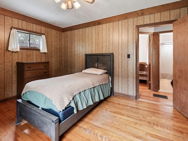 bedroom with visible vents, wood walls, and wood-type flooring
