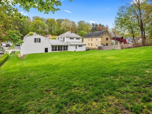 rear view of house with a yard, fence, and a chimney