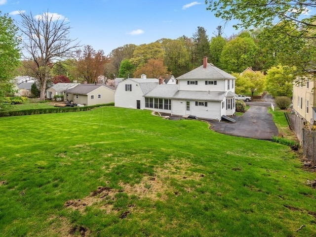 rear view of house featuring a chimney, a yard, a patio, and a residential view