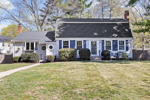 colonial inspired home with fence, a chimney, a shingled roof, and a front yard