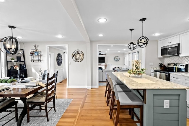 kitchen with an inviting chandelier, decorative backsplash, open floor plan, white cabinets, and stainless steel appliances