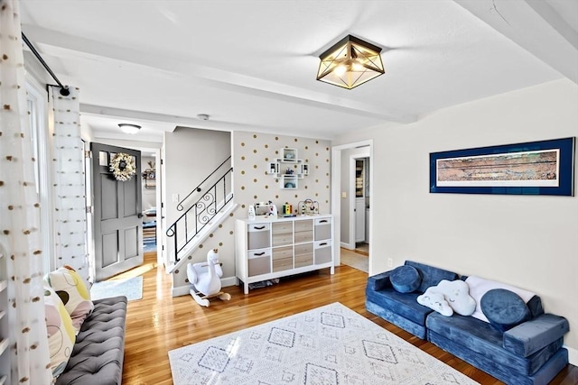 living area featuring wood finished floors, baseboards, stairs, and beam ceiling