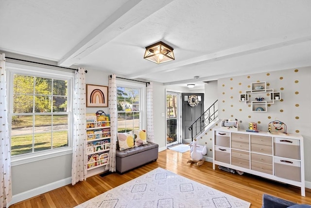 rec room with baseboards, beam ceiling, and light wood-type flooring
