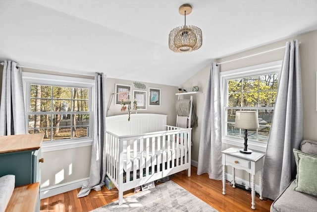 bedroom with baseboards, multiple windows, vaulted ceiling, and wood finished floors
