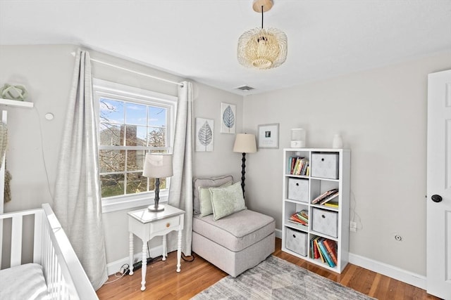 sitting room with baseboards, visible vents, and wood finished floors