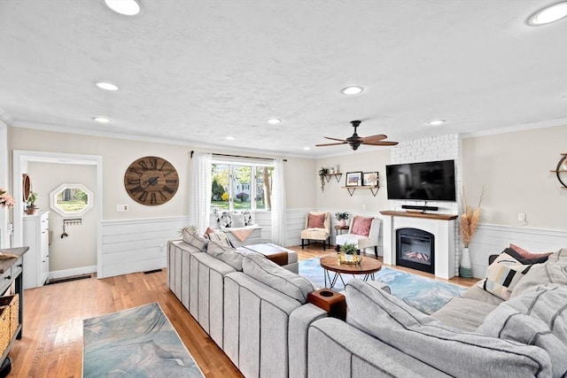 living room featuring recessed lighting, a ceiling fan, light wood-style flooring, and a wainscoted wall