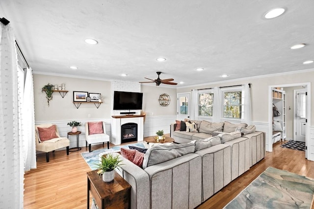 living area with ceiling fan, light wood-type flooring, a wainscoted wall, ornamental molding, and recessed lighting