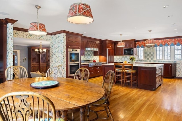 dining room featuring ornamental molding, sink, a chandelier, and light hardwood / wood-style floors