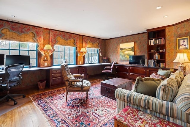 living room featuring built in desk, ornamental molding, and light hardwood / wood-style floors