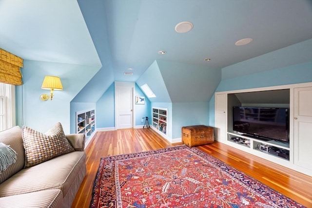 interior space featuring built in shelves, vaulted ceiling, and hardwood / wood-style flooring