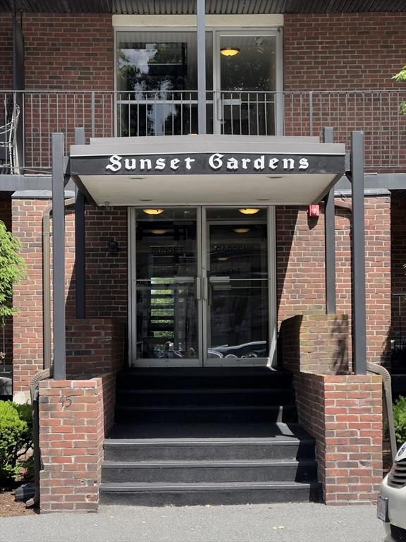 property entrance with brick siding and a balcony