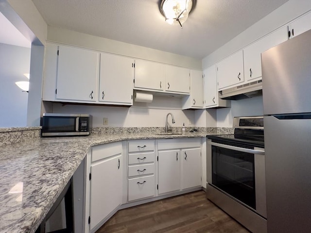 kitchen featuring dark wood-style flooring, stainless steel appliances, white cabinets, a sink, and under cabinet range hood