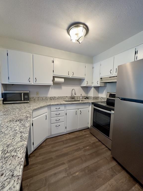 kitchen featuring under cabinet range hood, dark wood-style flooring, a sink, white cabinetry, and appliances with stainless steel finishes