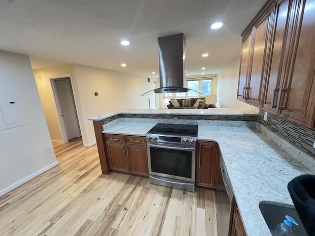 kitchen with stainless steel appliances, a peninsula, island exhaust hood, and light wood-type flooring