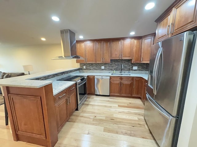 kitchen with brown cabinetry, appliances with stainless steel finishes, a sink, a peninsula, and extractor fan