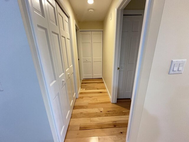 corridor with baseboards and light wood-style flooring