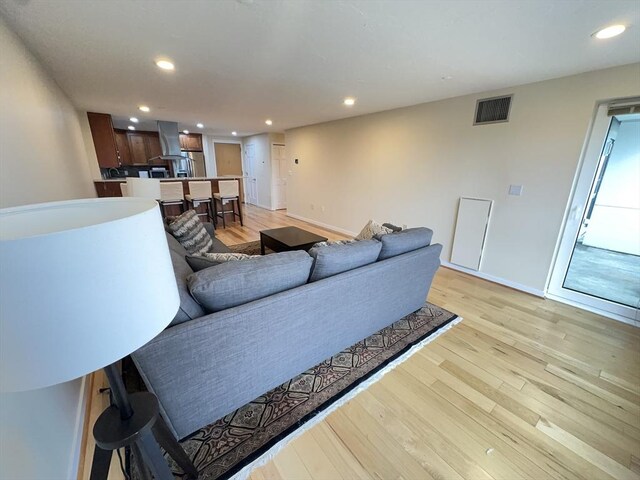 living area featuring visible vents, recessed lighting, baseboards, and light wood-type flooring