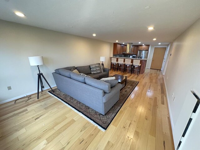 living room with baseboards, recessed lighting, and light wood-style flooring