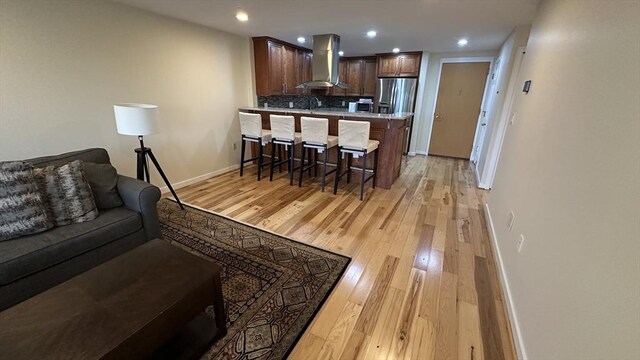living room with indoor bar, recessed lighting, baseboards, and light wood finished floors