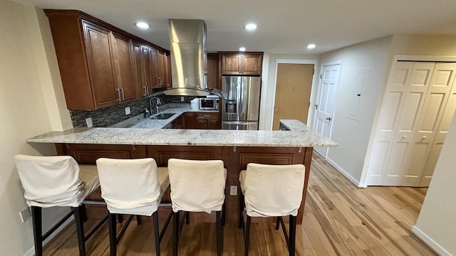 1001 Marina Dr Unit 213, Quincy, MA 02171 - kitchen featuring stainless steel appliances, island range hood, a peninsula, a sink, and light wood-style floors