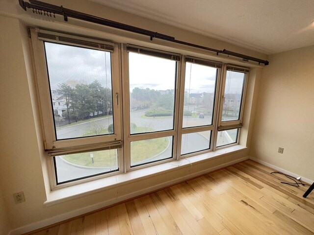 empty room featuring baseboards, light wood-style flooring, and a water view