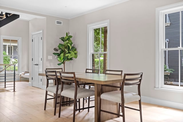 dining area with light hardwood / wood-style flooring and crown molding