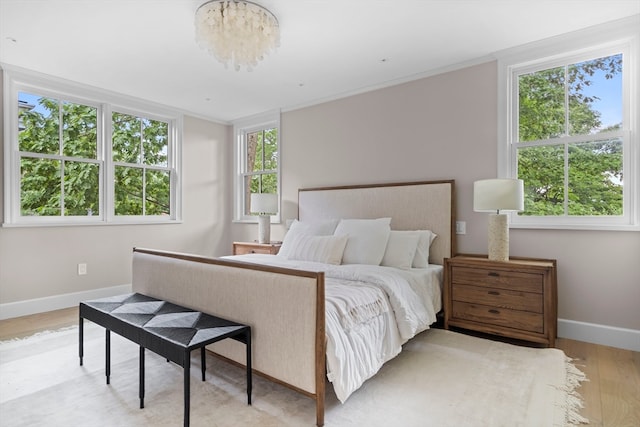 bedroom with light wood-type flooring and an inviting chandelier