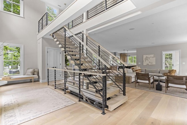 stairway with an inviting chandelier, a high ceiling, and wood finished floors