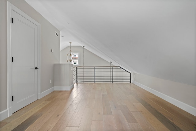 additional living space with lofted ceiling, a chandelier, and light wood-type flooring