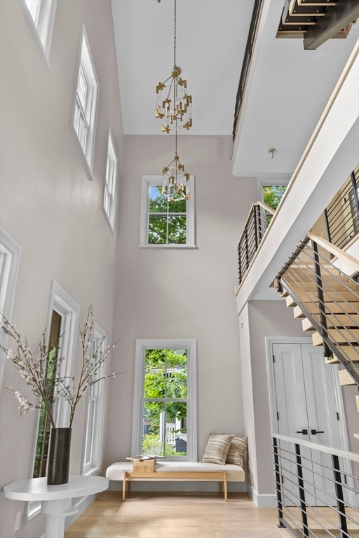 foyer entrance with a towering ceiling, an inviting chandelier, and light hardwood / wood-style flooring