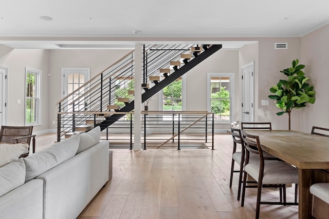 living room featuring a wealth of natural light, light hardwood / wood-style flooring, and ornamental molding