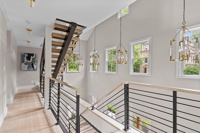 stairs with wood-type flooring, a notable chandelier, and plenty of natural light