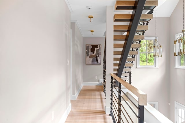 stairway with a notable chandelier, crown molding, and hardwood / wood-style floors