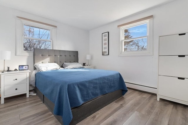 bedroom featuring multiple windows, light hardwood / wood-style flooring, and baseboard heating