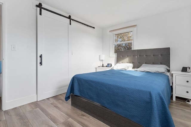 bedroom featuring a barn door and light hardwood / wood-style flooring