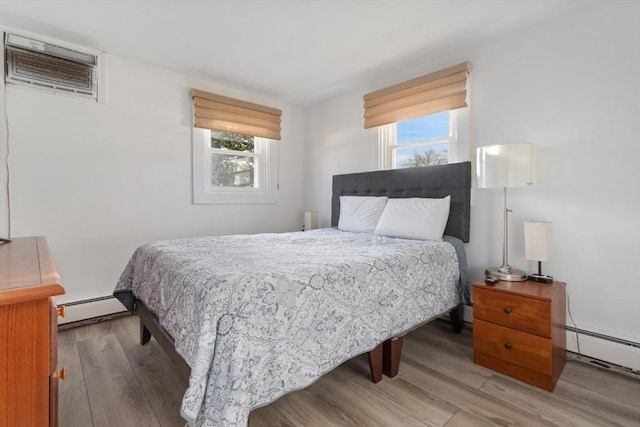 bedroom featuring hardwood / wood-style floors, baseboard heating, and a wall unit AC